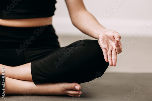 Close up of young women practicing yoga the easy sitting pose (sukhasana) in the living room, Lotus pose on meditation, work out at home, wellness concept.