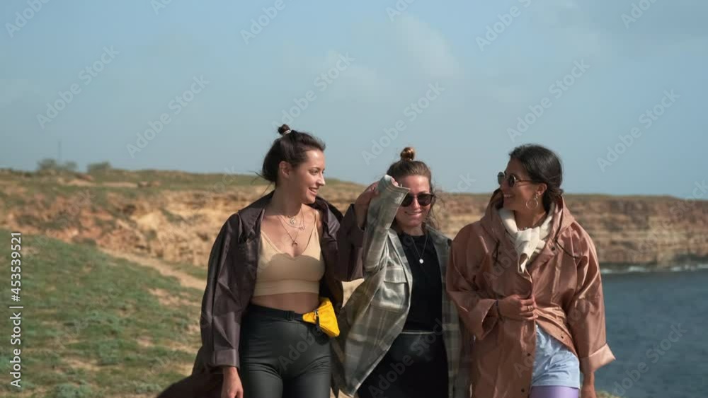 three happy women are walking on high sea coast three happy women are walking on high sea coast