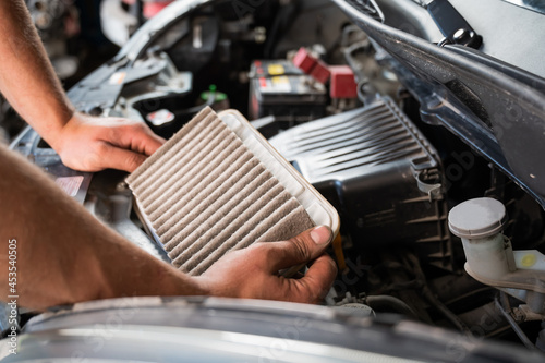 An auto mechanic is changing the air filter in the car