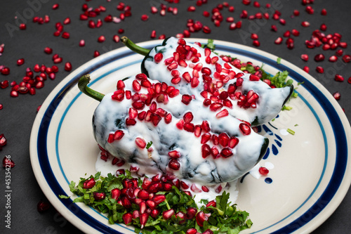 Chile en Nogada, a traditional dish from Puebla with the addition of walnut cream, pomegranate seeds and parsley on black background photo
