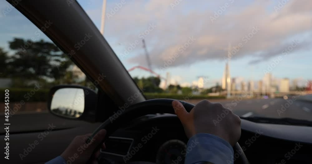 Driving car on sunrise city road, hands holding the steering wheel Driving car on sunrise city road, hands holding the steering wheel