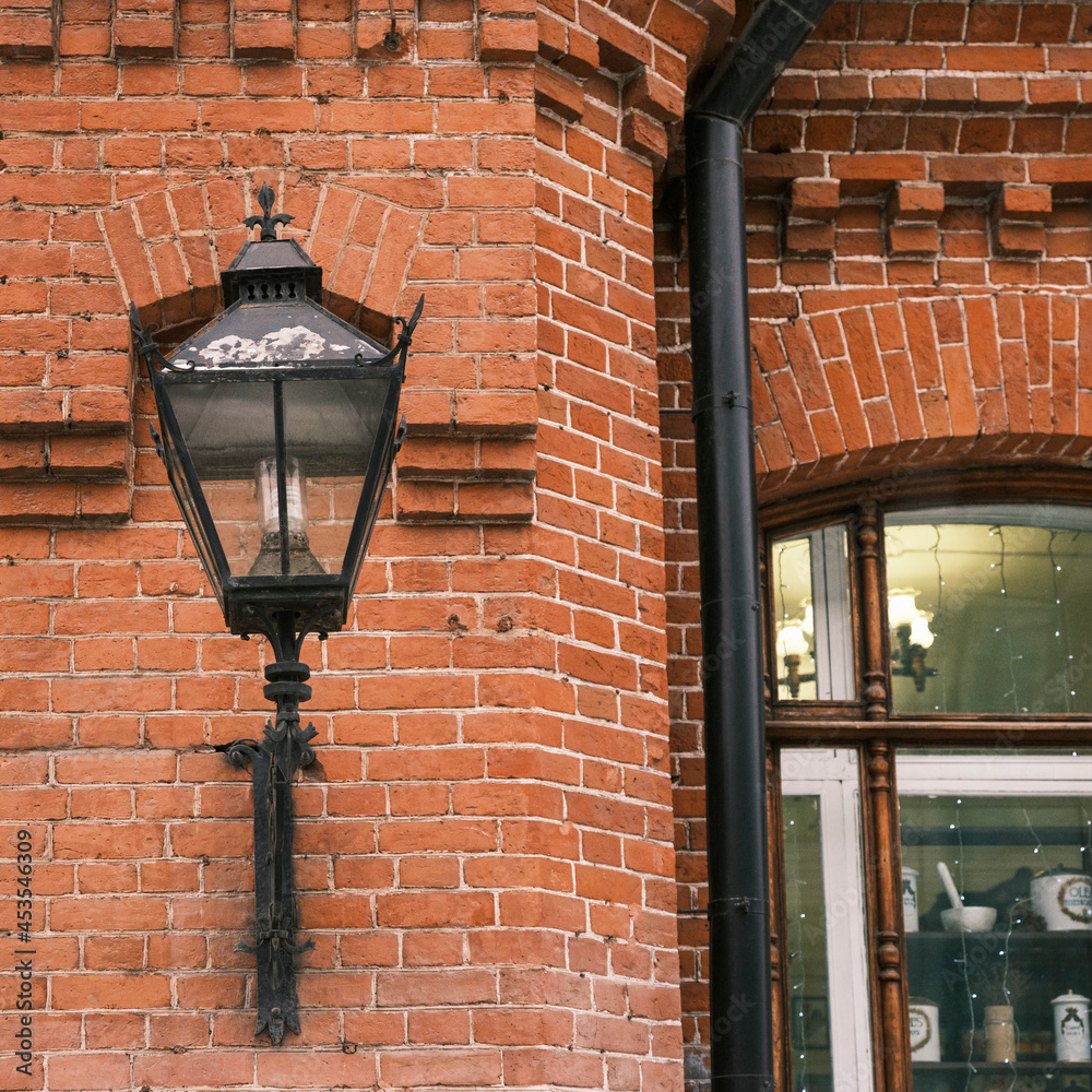Vintage lantern on a brick wall of an old building. Window with lights and decoration.
