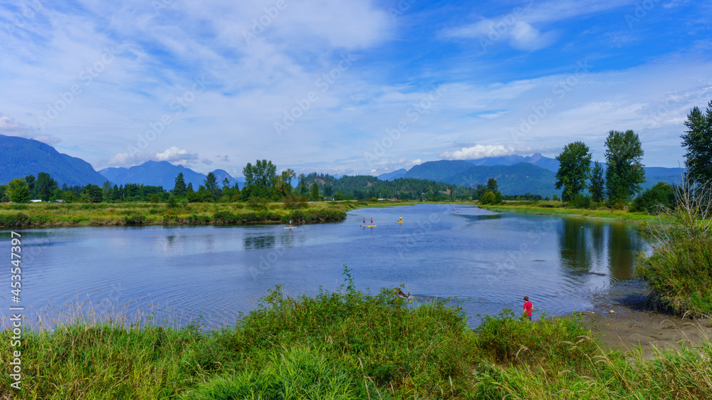 Paddle-boarders on peaceful BC river in spectacular surroundings