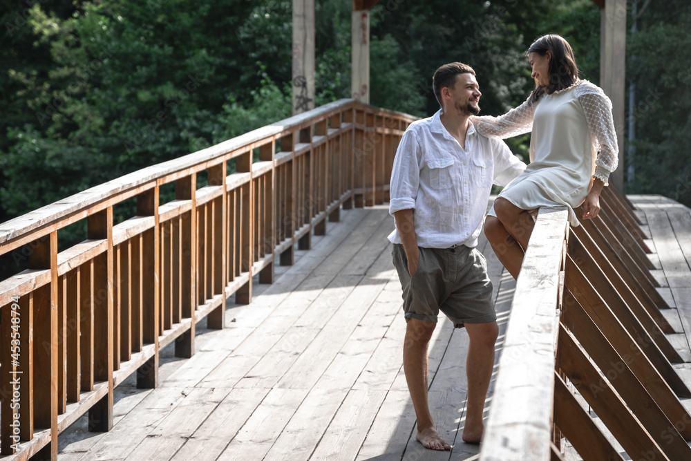 Smartly dressed man and woman on a wooden bridge in the forest.