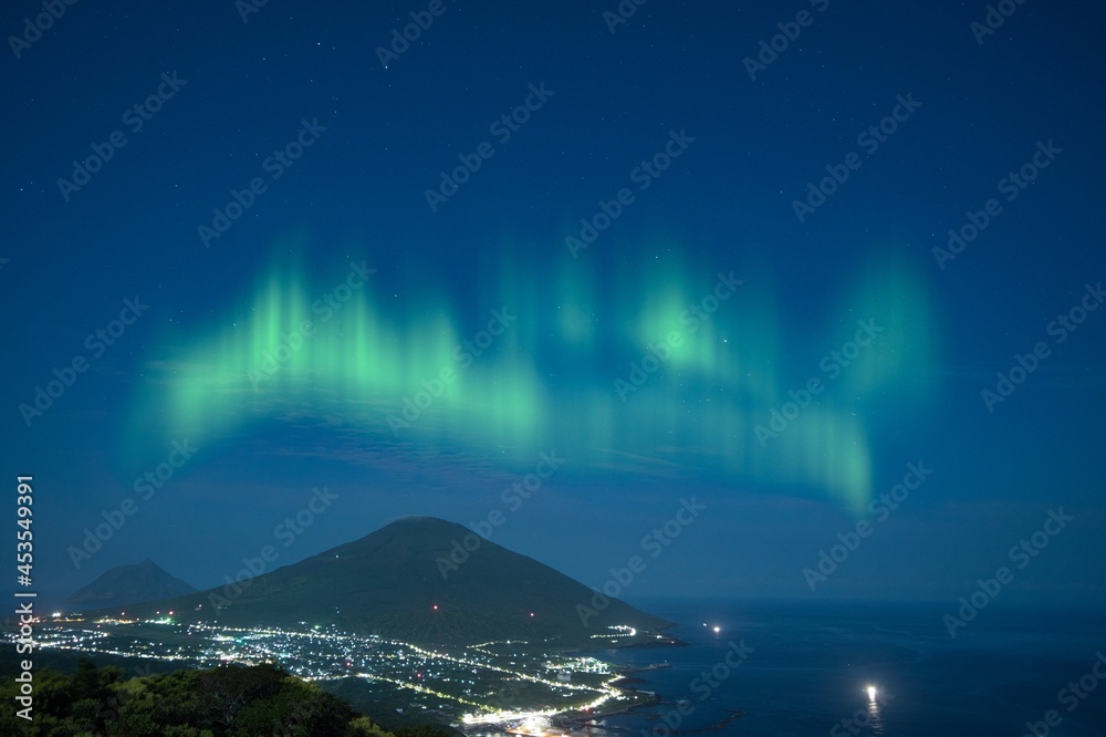 The Northern lights with mountain and city lights in the night at Norway