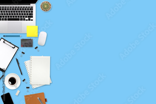 flat lay workspace table with laptop computer, office supplies, coffee cup, tablet and cell phone on blue pastel background
