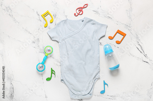 Stylish baby clothes with toy and bottle on white background