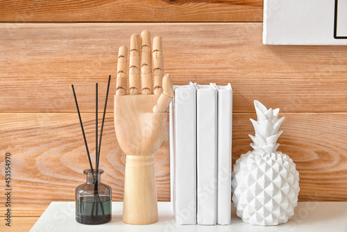 Stylish decor and reed diffuser on table near wooden wall