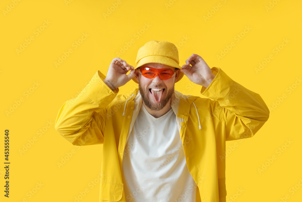 Handsome young man showing tongue on color background