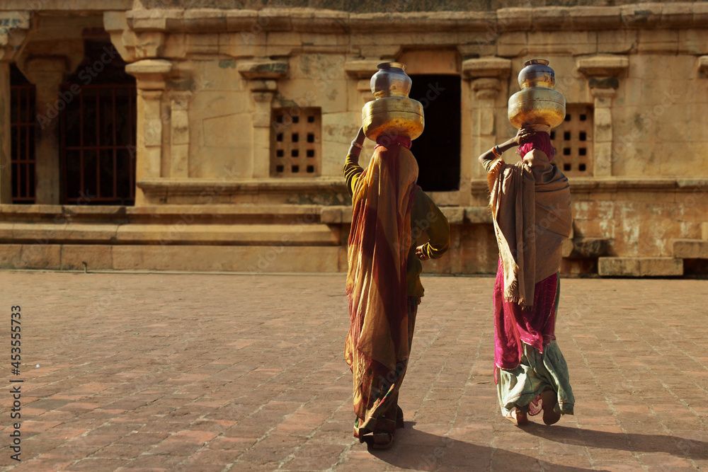 indian woman wearing saree walking with basket on her head indian woman wearing saree walking with basket on her head