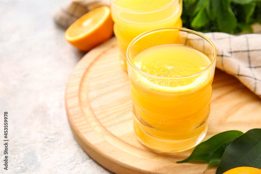 Fototapeta premium Freshly squeezed orange juice in glass with citrus slice, healthy beverage on wooden board, refreshing drink for wellness