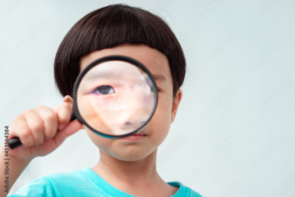 Boy focusing on magnifying glass He was serious about searching for something. Boy focusing on magnifying glass He was serious about searching for something.