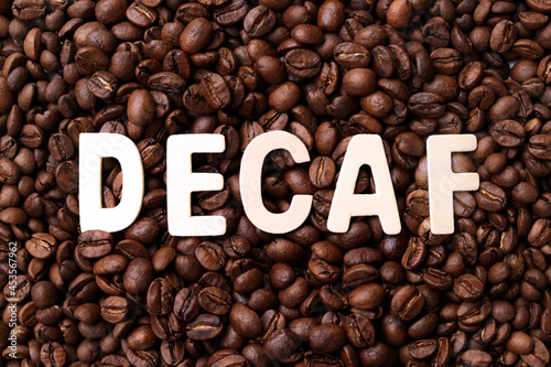 Decaf coffee word on roasted coffee beans background. Concept of decaffeinated coffee or low caffeine coffee. photo