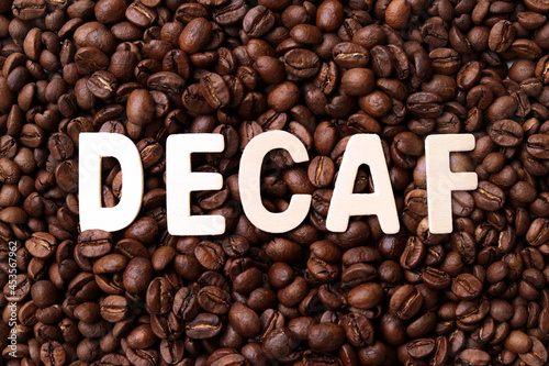 Decaf coffee word on roasted coffee beans background. Concept of decaffeinated coffee or low caffeine coffee.