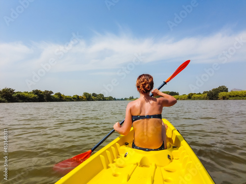 A young woman in the canoe canoeing in a natural park in Catalonia, a river next to the beach in Estartit