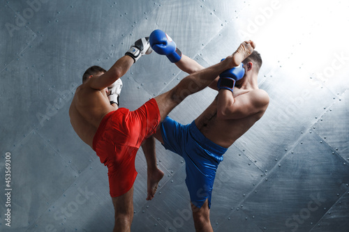 Two men boxers fighting muay thai kickboxing hgh kick steel background.