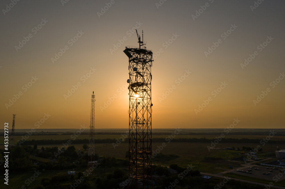 The sun shines through the silhouette of telecommunication towers