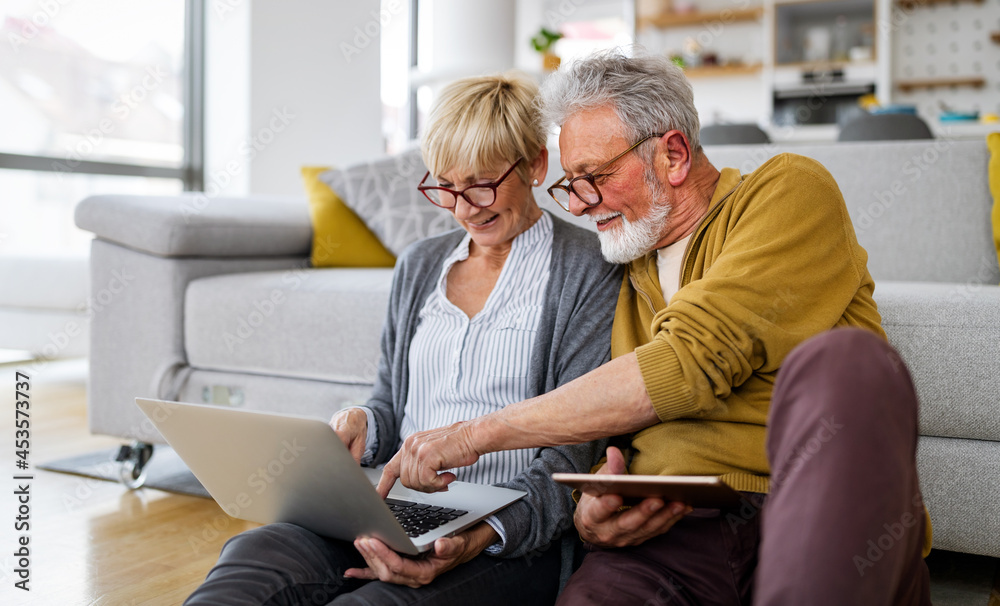 Cheerful senior couple using technology devices and having fun at home Cheerful senior couple using technology devices and having fun at home