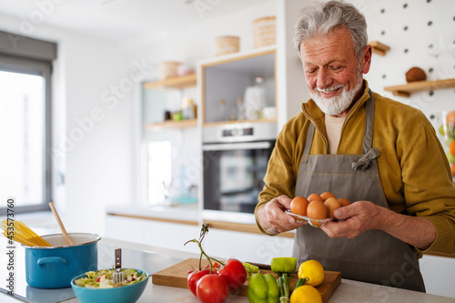 Mature handsome man cooking in home kitchen