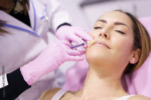 Doctor injecting hyaluronic acid in the face of a woman as a facial rejuvenation treatment.