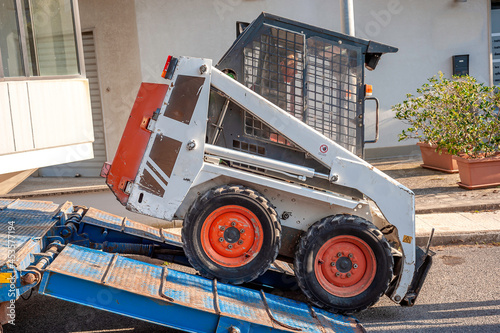 mini excavator transported on the truck, by means of ramps it is unloaded by an operator