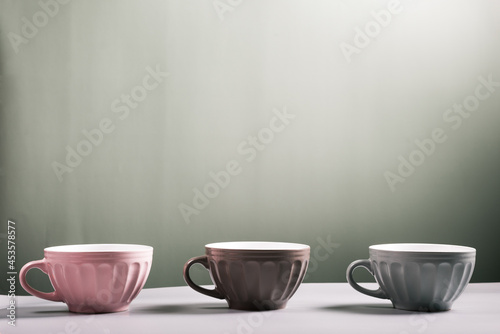 three cute empty ceramic coffee cups pastel colors and rowan branch