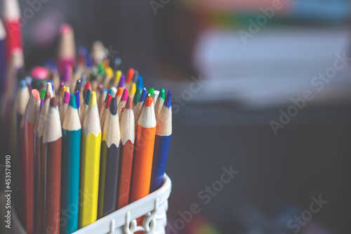 There are a lot of colored pencils standing vertically in a stationery stand. A set for fine art.