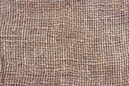 Natural burlap with large cells. The texture of a coarse woven fabric with mesh and fibers.