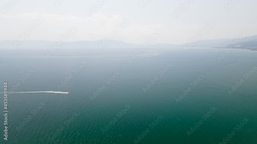 Panoramic drone clip of a small tropical peninsula with a boat passing by in Strimonas, Macedonia, North Greece