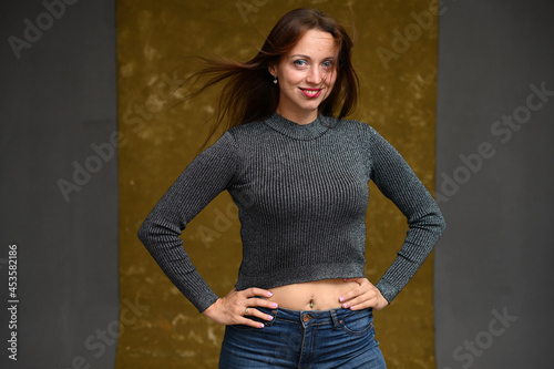 Smiling woman in studio posing with flying hair on gray and beige background