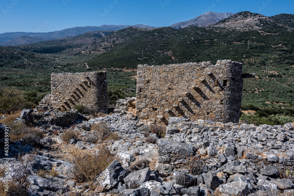 ancient stone mills and their ruins on the slopes of the mountains in Crete on a sunny day