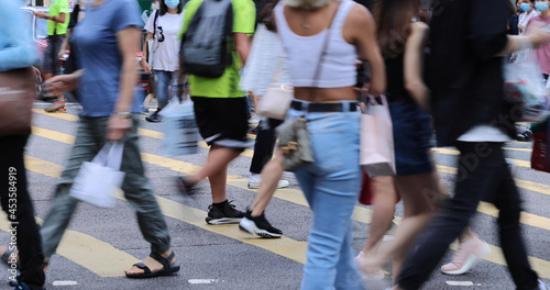 blurred Busy crowds of men and women or Commuters Crossing Street in Central, Hong Kong, with Crosswalk yellow lines. zebra yellow pedestrian crossing