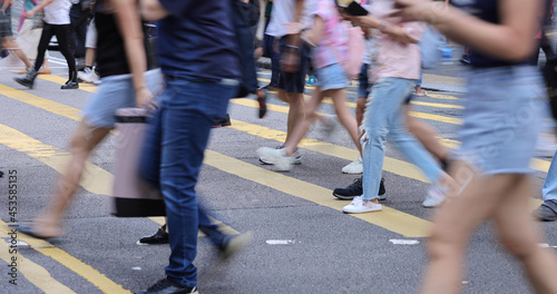 blurred Busy crowds of men and women or Commuters Crossing Street in Central, Hong Kong, with Crosswalk yellow lines. zebra yellow pedestrian crossing