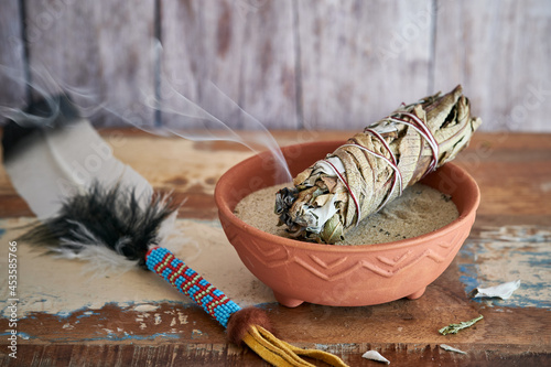 Smudge Stick Weißer Salbei und Yerba Santa in einer Tonschale mit Räucherfeder photo