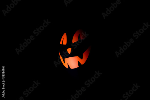 Halloween scary black air balloon with orange face on a black background.Minimalistic Halloween background.Copy space for text.