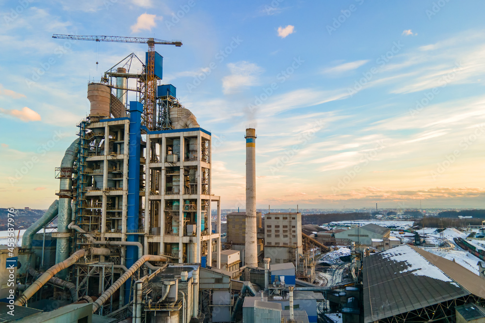 Aerial view of cement plant with high factory structure and tower crane at industrial production area at sunset. Aerial view of cement plant with high factory structure and tower crane at industrial production area at sunset.