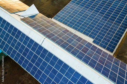 Blue photovoltaic solar panels mounted on industrial building roof for producing clean ecological electricity. Production of renewable energy concept.