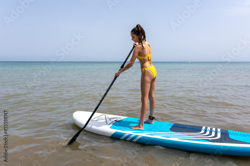 Girl on her back paddling on top of a paddle surf board in the sea. © FranciscoJavier