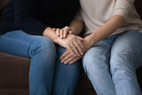 Close up young woman covering hands of middle aged retired mother, involved in sincere trusted conversation. Happy sincere multigenerational female family enjoying sweet tender moment at home.