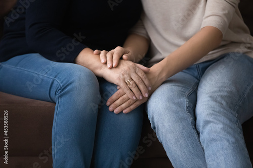 Fototapeta Naklejka Na Ścianę i Meble -  Close up young woman covering hands of middle aged retired mother, involved in sincere trusted conversation. Happy sincere multigenerational female family enjoying sweet tender moment at home.