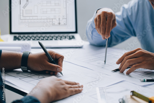 architect drawing on a blueprint on architectural project at the construction site at office desk in the office.Architectural and engineering concept. photo