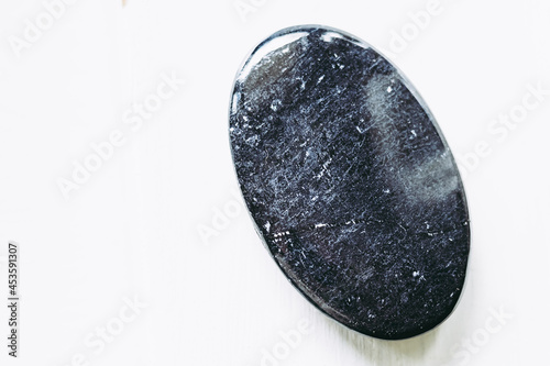 Galet pierre roulée polie tourmaline noire sur un fond blanc - Minéral naturel photo