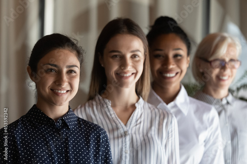 Head shot portrait successful motivated diverse businesswomen employees showing unity, standing in row, four smiling workers coworkers team feeling motivated, employment and recruitment concept