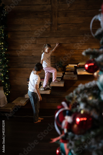 happy kids in pajamas playing on christmas morning near christmas tree