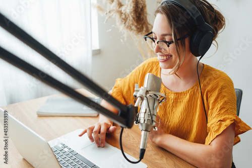 Tablou pe pânză Cheerful woman host streaming his podcast using voice microphone