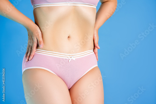 Slim woman in pink underwear on blue background