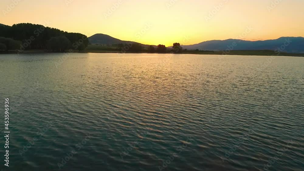Lake view at sunset. The red of the sun reflects on the lake. Sunset behind the mountains. Lake view at sunset. The red of the sun reflects on the lake. Sunset behind the mountains.