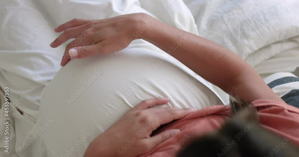 Pregnany woman tracing her finger around her belly as she sings to her unborn baby - close up from above Pregnany woman tracing her finger around her belly as she sings to her unborn baby - close up from above