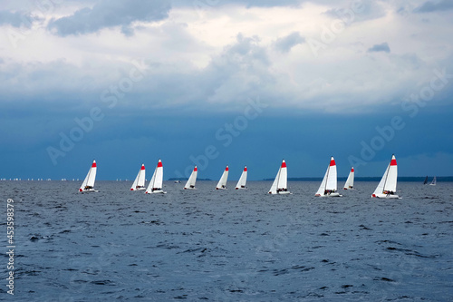 Many sailboats in the open sea. Sailboats participate in sailing regatta in stormy cloudy weather