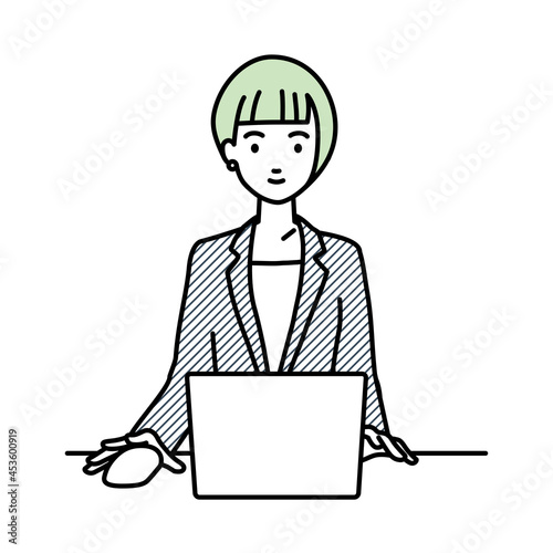 デスクで座ってPCを使っているスーツの女性